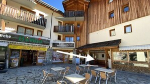 Un patio con suelo de piedra, mobiliario exterior y un edificio con balcones de madera.