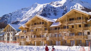 Un hotel de estilo chalé de madera con varios balcones, con montañas nevadas al fondo.