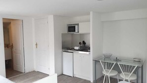 A compact kitchen with white cabinets, a microwave, a sink, and a small dining area with two chairs. - Tours-Fondettes - Touraine Loire Valley (Fondettes)