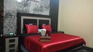 Una habitación de hotel con una cama, una mesita de noche, una cómoda y una pared con diseño de mármol.