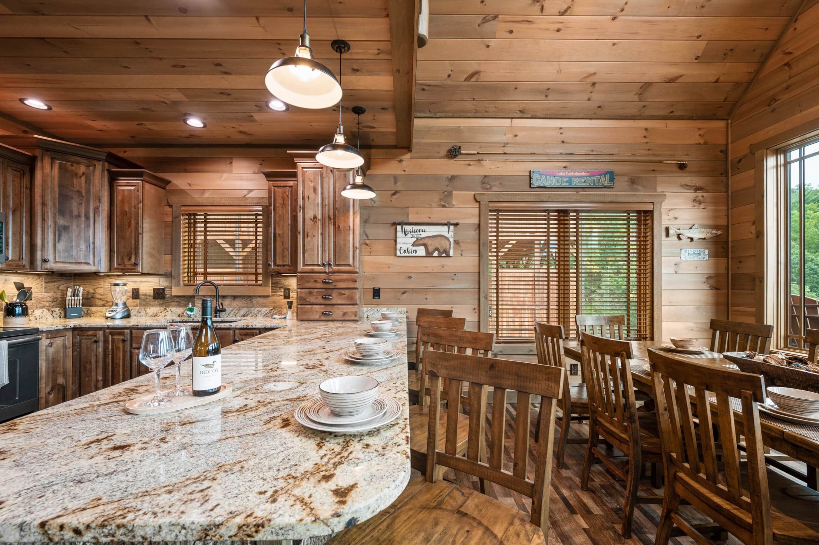 A wooden cabin interior with a kitchen island, dining area, and a sign indicating 'Canoe Rental.'