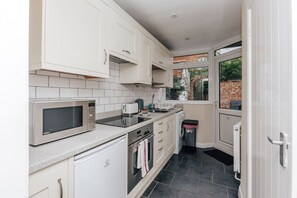 A compact kitchen with white cabinets, a microwave, a toaster, and a small sink. - Honeysuckle Terrace - From 125 Per Night (Henley-on-Thames)