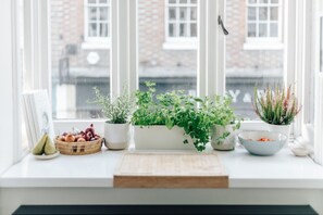 A window sill with potted plants, a wooden cutting board, and a bowl of fruit. - Central Hidden Gem - From 125 Per Night (Henley-on-Thames)