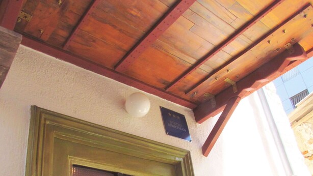 A wooden ceiling with a sloped design, a green-framed window with a decorative grille, and a plaque on the wall. - TRAVELLER FRIENDLY APARTMENT IN SUNNY PULA CITY IN BEAUTIFUL ISTRIAN COUNTY (Pula)