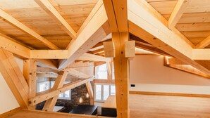 Un'ampia stanza mansardata con travi a vista in legno e soffitto inclinato.