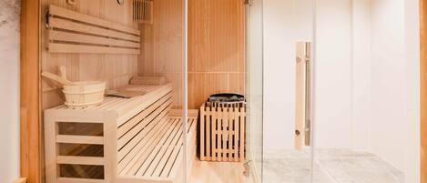 A sauna with wooden benches, a wooden bucket, and a small trash bin.