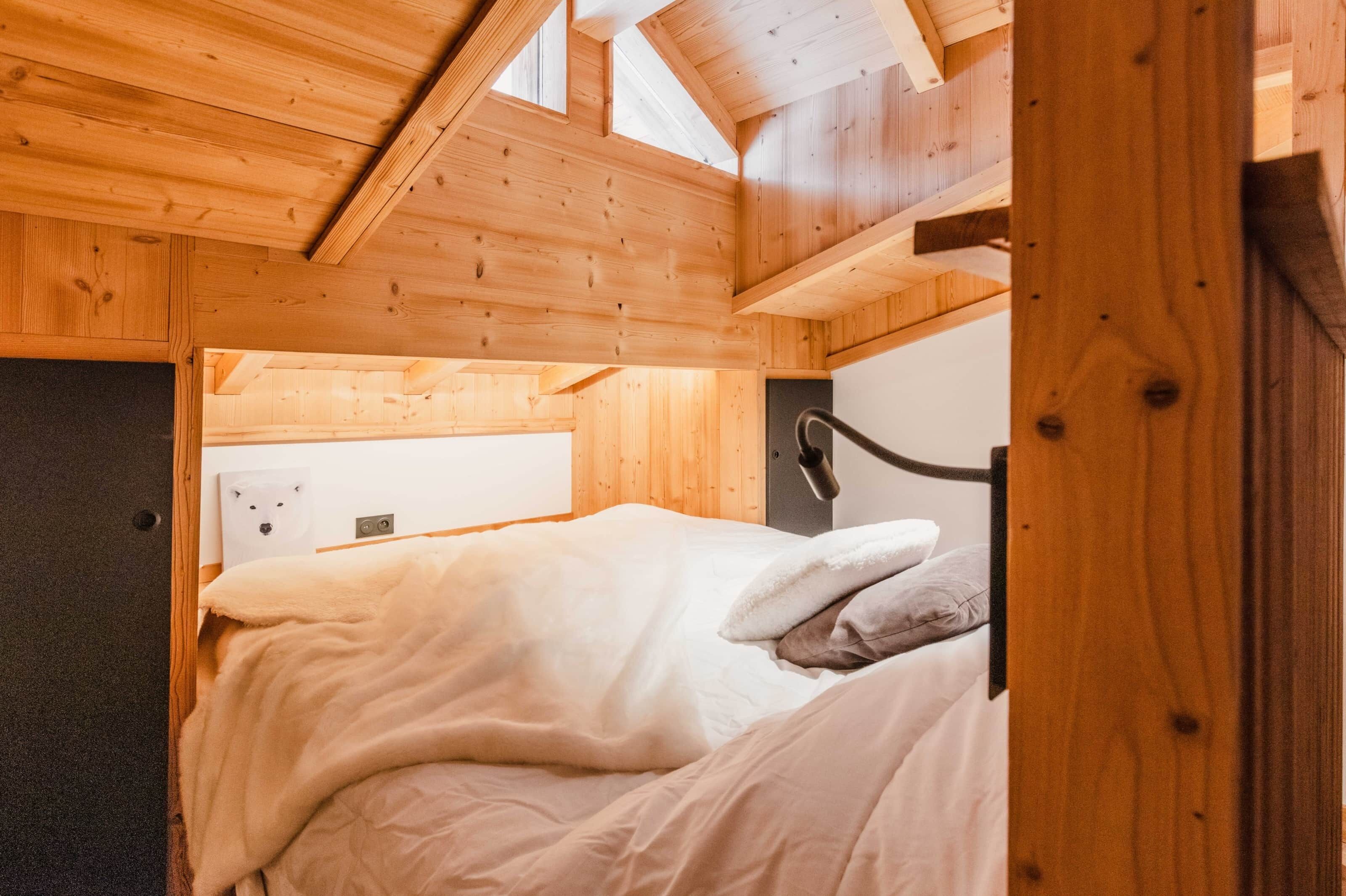 Een slaapkamer in houten blokhutstijl met een bed, een hoofdbord en een dakraam.