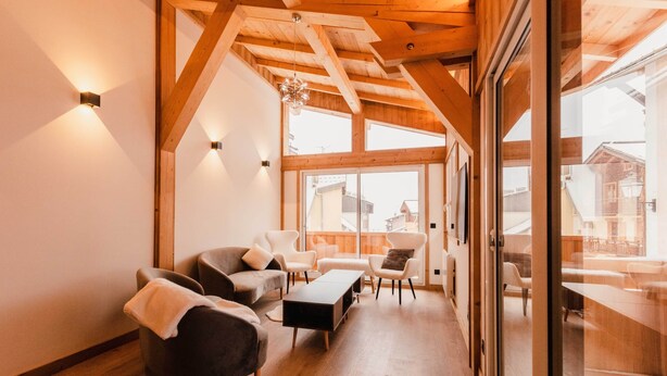 Un'ampia zona giorno con travi in legno, un divano, poltrone e un tavolino.