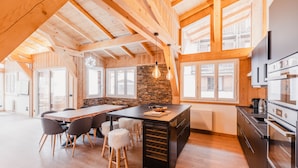 Una cucina moderna con travi in legno, un'isola centrale e una parete decorativa in pietra.