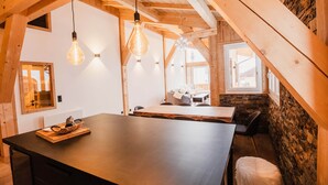 Una cucina moderna con un'isola grande, travi in legno e lampade a sospensione.