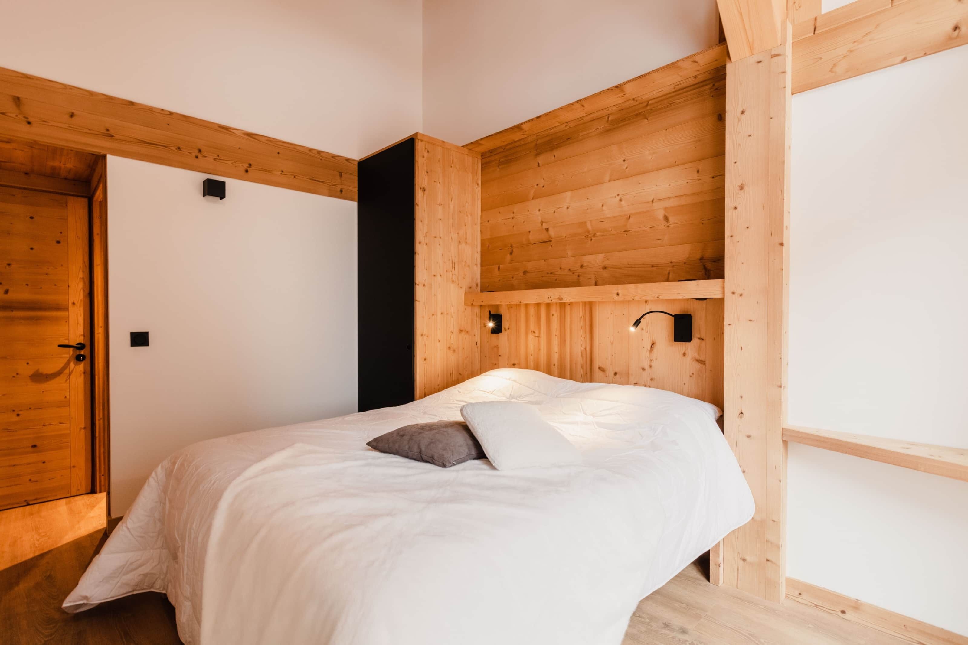 Un dormitorio con techo de madera, cama con ropa de cama blanca y puerta de madera.