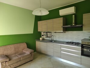 A modern kitchen with light wood cabinets, a gas stove, and a built-in oven.