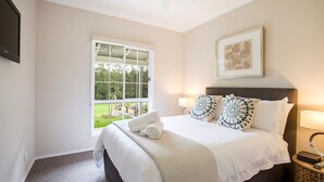 Une chambre d’hôtel avec une grande fenêtre, un lit recouvert de draps blancs et une œuvre d’art encadrée au-dessus du lit.