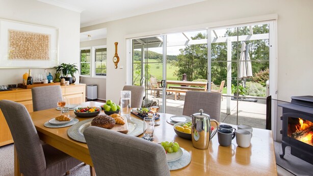 Un coin repas avec une table dressée pour le repas, une cheminée et une vue sur l’extérieur.