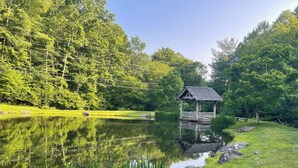 Un belvédère en bois, situé au bord d’un lac paisible, entouré d’une végétation luxuriante.