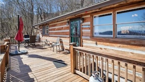Une cabane en bois dotée d’une terrasse, de meubles d’extérieur et d’une grande fenêtre.