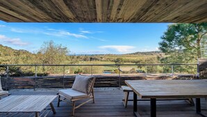 A wooden deck with a table and chairs, overlooking a scenic landscape with hills and trees. - A1: Apartment for 6 pers., terrace, sea view, 400 m from the beach (Zonza)