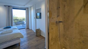 A modern bedroom with a large bed, a television mounted on the wall, and a sliding glass door leading to a balcony. - A1: Apartment for 6 pers., terrace, sea view, 400 m from the beach (Zonza)