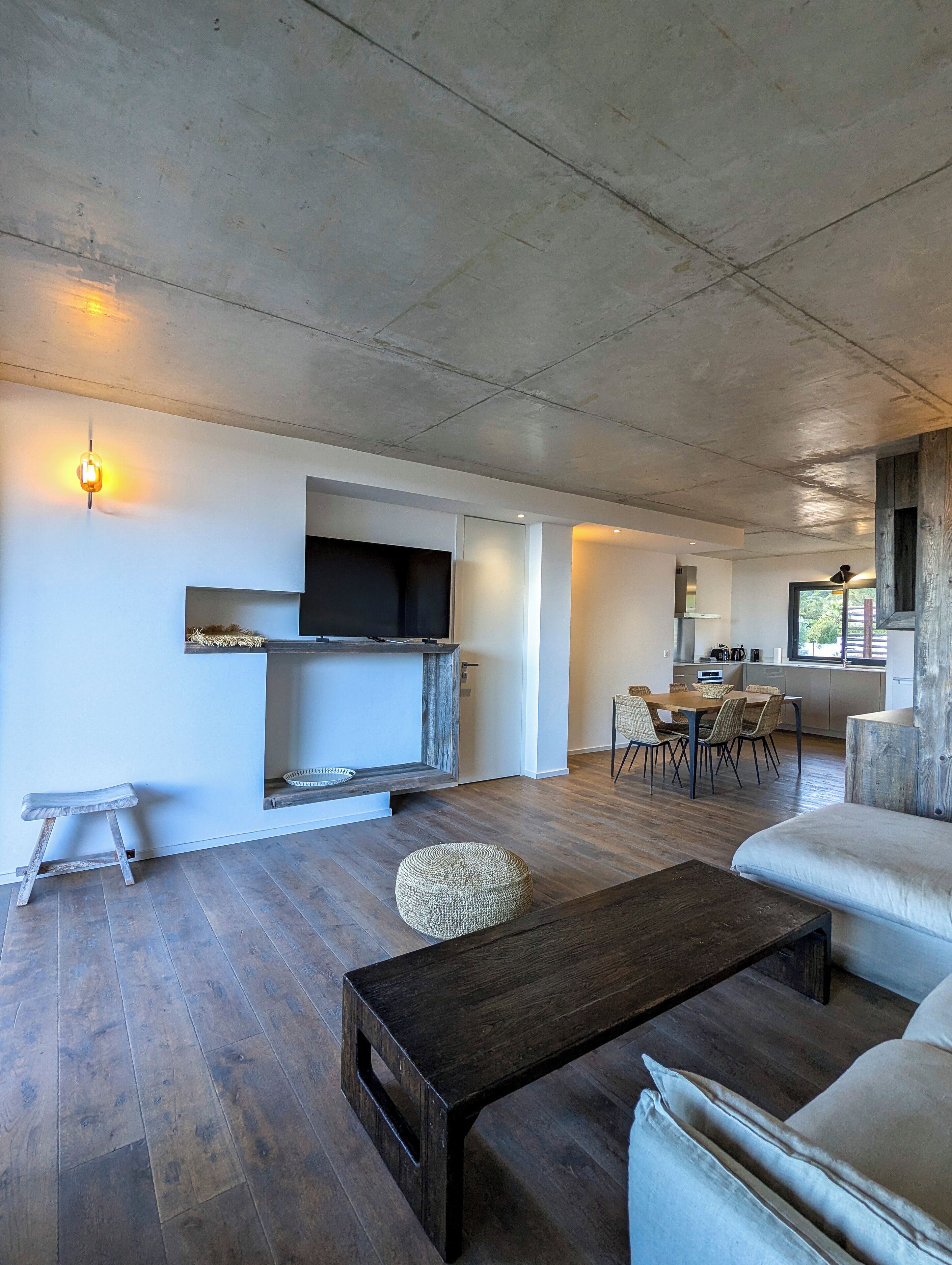 Ein modernes Wohnzimmer mit einem Holztisch, einer Couch und einem Essbereich mit Stühlen.