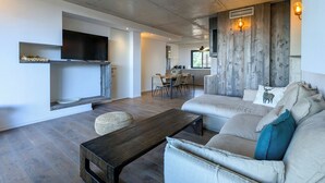 A modern living room with a sofa, coffee table, and a flat-screen TV mounted on the wall. - A1: Apartment for 6 pers., terrace, sea view, 400 m from the beach (Zonza)
