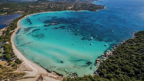 An aerial view of a coastal area with clear turquoise waters, a sandy beach, and scattered boats. - A1: Apartment for 6 pers., terrace, sea view, 400 m from the beach (Zonza)