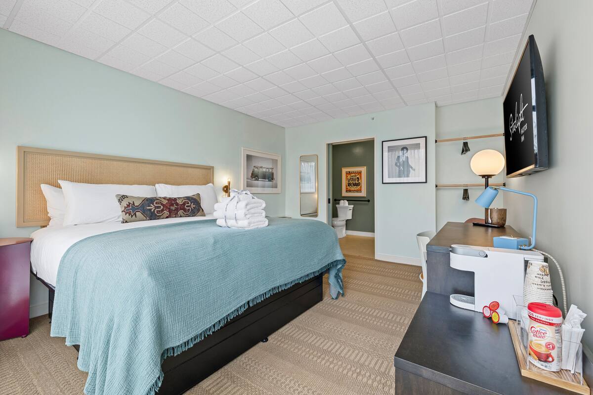 Hotellihuone, jossa on sänky, työpöytä, televisio ja kahvinkeitin.