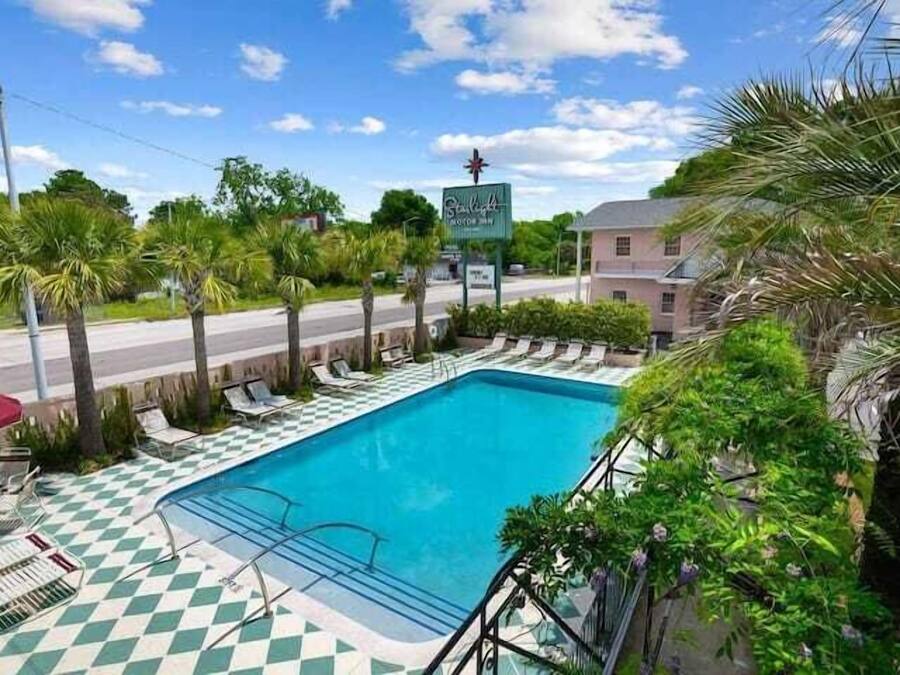 A pool area with a checkered floor, lounge chairs, and a sign for the "Sunshine Motor Inn".