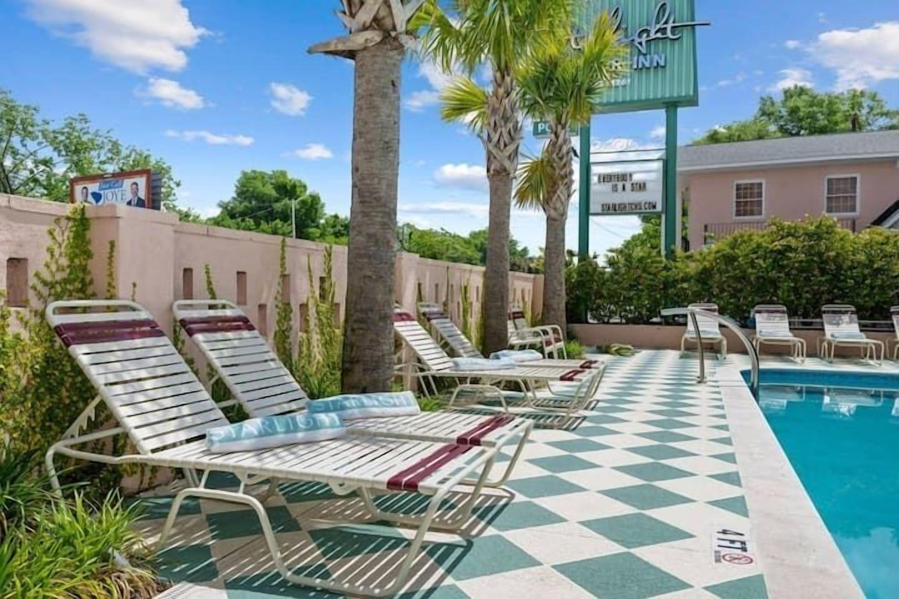 A pool area with lounge chairs, palm trees, and a sign for 'The Ritz-Carlton'.