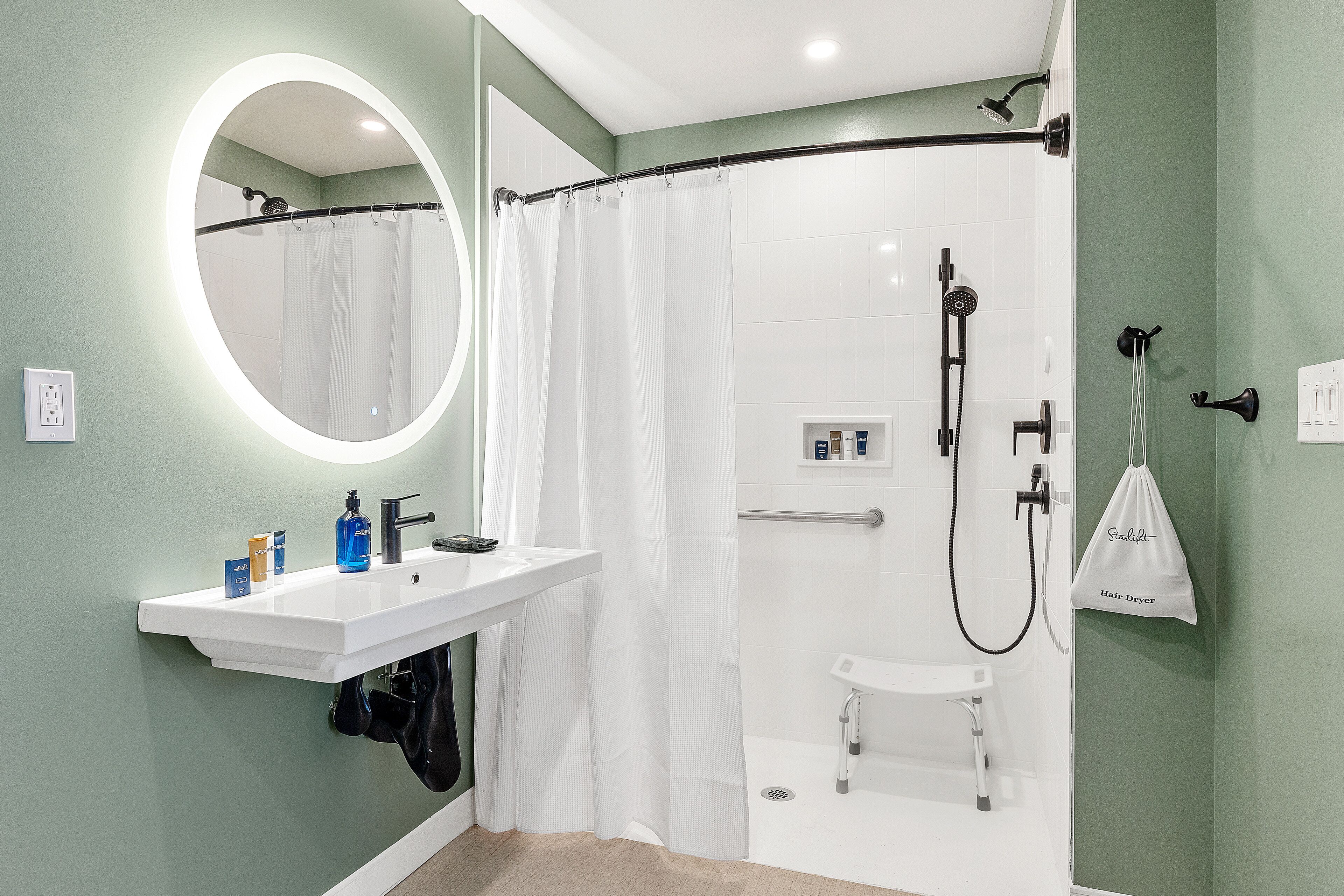 Un baño con un lavamanos blanco, espejo y ducha.