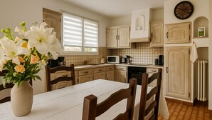Una cucina con mobili in legno, un piano di lavoro bianco e un tavolo da pranzo con sedie.