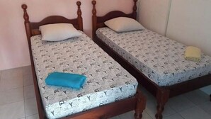Deux lits simples avec des têtes de lit en bois et une literie à motifs.