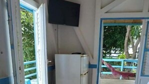 Une pièce de taille modeste, avec une commode en bois, un réfrigérateur blanc et un téléviseur fixé au mur.