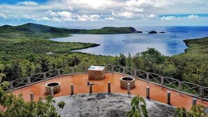 Un belvédère offrant une vue panoramique, avec une plateforme d’observation circulaire, une rambarde en métal et un banc en pierre.