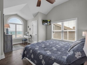 A bedroom with a large bed, a desk, a chair, a TV, and a window with blinds. - July 11-18 Cancellation Discount! Oceanfront Home with Direct Beach Access! (Myrtle Beach)