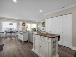 Una cocina con armarios blancos, encimera de madera y un comedor con sillas y mesa blancos.