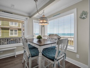 A dining area with a table, chairs, and a view of the ocean.