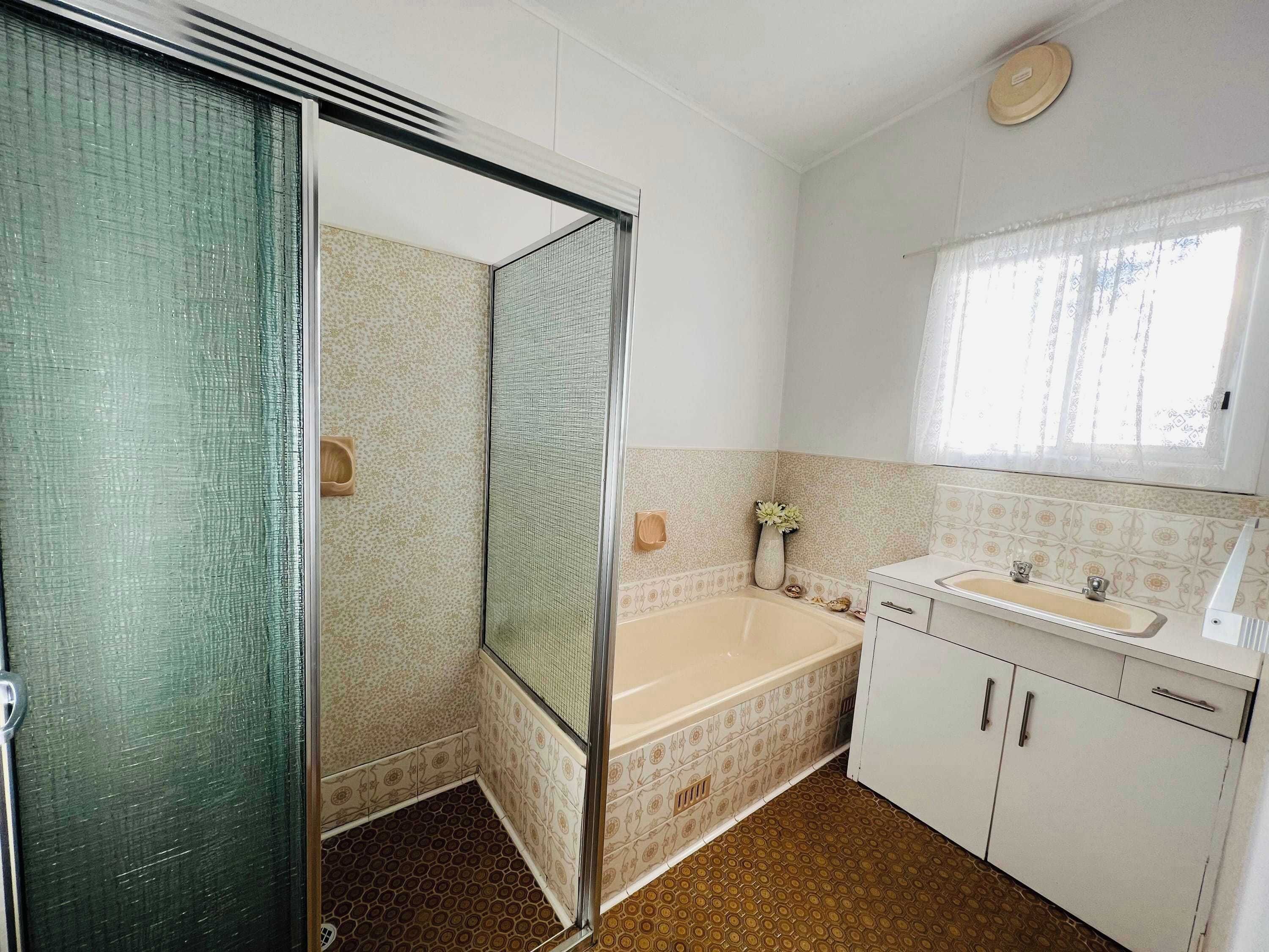 A bathroom with a shower, bathtub, sink, and cabinets.