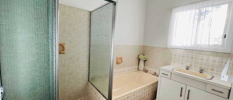 A bathroom with a shower, bathtub, sink, and cabinets.