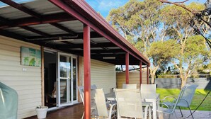 A covered patio with a table and chairs, a sliding glass door, and a view of the backyard.