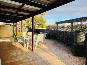 An outdoor patio with a table and chairs, a covered area, and a view of the backyard. - Teddy's Shack  -Pet friendly outside (Robe)