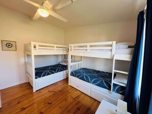 A room with two bunk beds, wooden flooring, a ceiling fan, and a framed picture on the wall. - Teddy's Shack  -Pet friendly outside (Robe)