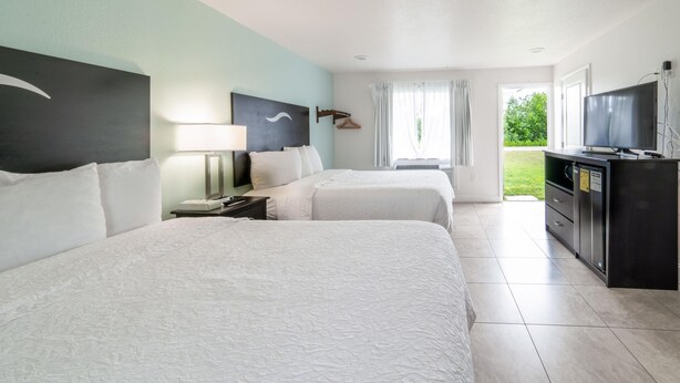 Ein Hotelzimmer mit zwei Betten, einem Fernseher, einem Schreibtisch und Blick ins Freie.