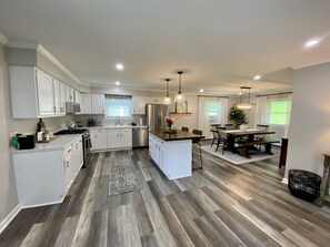 A spacious kitchen with white cabinets, a central island, and a dining area with a table and chairs. - Newly Remodeled 3-Bedroom Pet Friendly Home (Eglon)