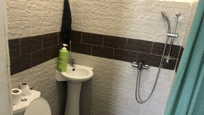 Ein Badezimmer mit Toilette, Waschtisch und Dusche.