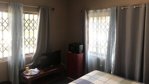 Ein Hotelzimmer mit einem Bett, einem Fernseher auf einem Schrank, einem kleinen Tisch mit einer Auflage und einer Klimaanlage an der Wand.