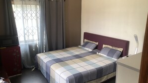 Ein Schlafzimmer mit Bett, Vorhängen, einem Fenster und einer Mikrowelle.