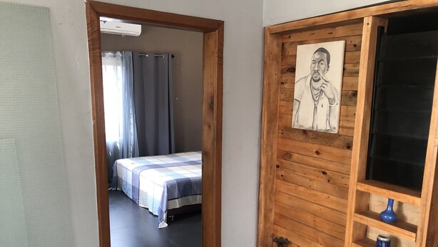 Ein Zimmer mit einem Bett, einem Holzregal mit Dekoration und einem Bild an der Wand.