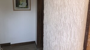 Een gang met een ingelijst kunstwerk aan de muur en een gestructureerde wand aan de rechterkant.