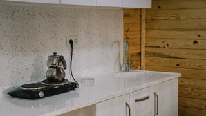 A kitchen with a speckled countertop, a coffee maker, and wooden paneling on the wall. - Agva Marina House (Sile)
