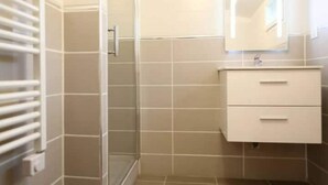 Een badkamer met beige tegels, een witte wastafel en een spiegel.